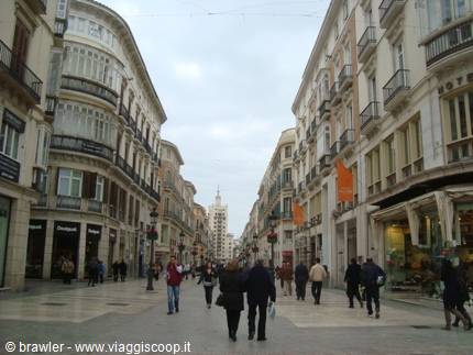 Pedestrians walking along Calle Larios in Malaga, balconied buildings, grey sky