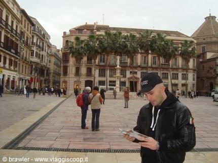 Tourist holding a map in a Malaga square, palm trees and historic buildings