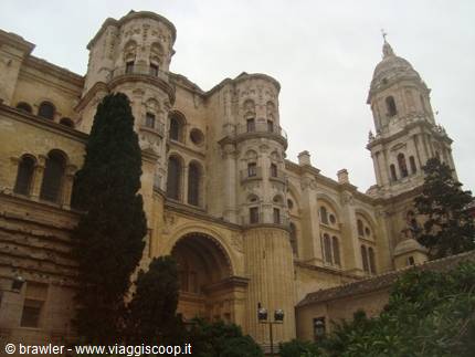 Malaga Cathedral, Renaissance stone facade, cypress tree and bell tower under a grey sky