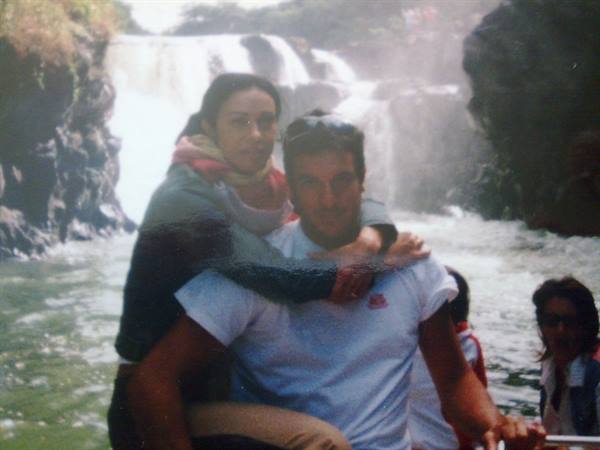 Couple on a boat in front of a waterfall among dark rocks