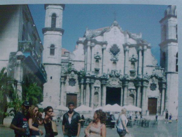 Tourists walking in front of Havana Cathedral, baroque stone facade under the sun