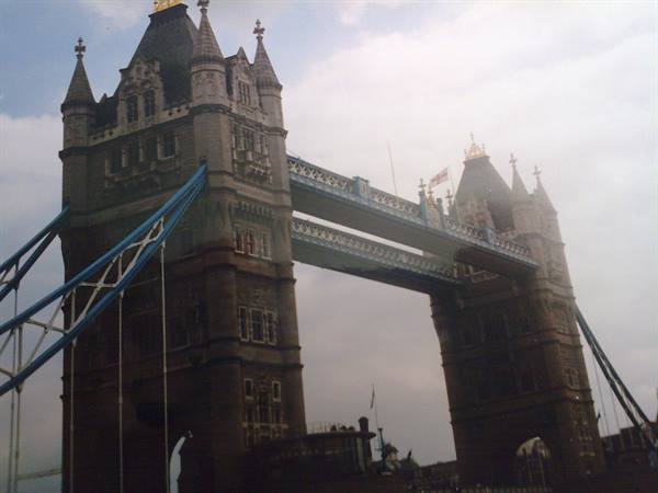 The stone towers of Tower Bridge in London under a cloudy sky