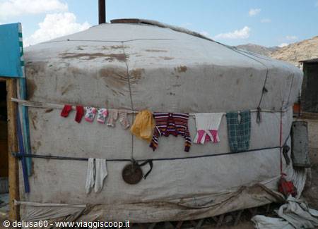 Worn felt yurt with laundry drying on a rope, sunny day