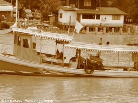 Wooden river boat with canopy, stilt houses in background