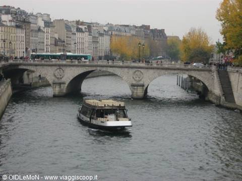 Tourist boat on the Seine under Pont Neuf in Paris, grey autumn sky