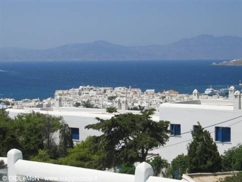 whitewashed Mykonos houses above the blue sea, distant mountains