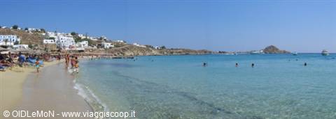 Swimmers in turquoise water at Platis Gialos, white buildings along the beach
