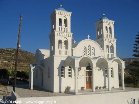 White church with twin bell towers and crosses under blue sky