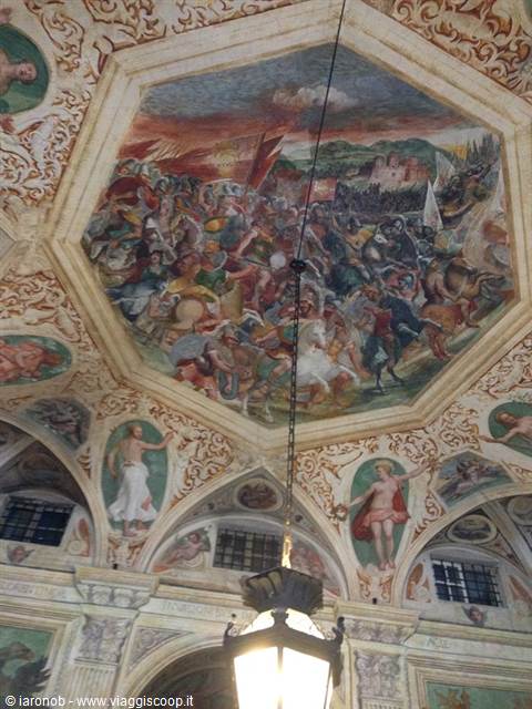 Frescoed ceiling with battle scene, wrought iron lantern glowing below