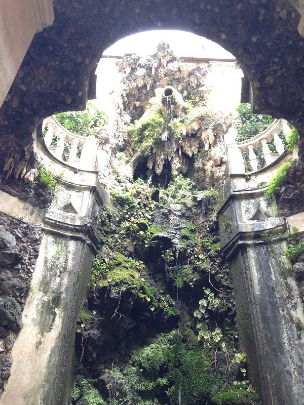 Fontana barocca incrostata di muschio e conchiglie tra colonne e balaustra in pietra