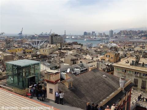 Genoa rooftops seen from the terrace, tourists, harbor with cranes in background
