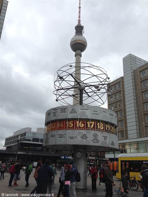 World clock and TV Tower at Alexanderplatz, Berlin, cloudy sky, tourists passing by