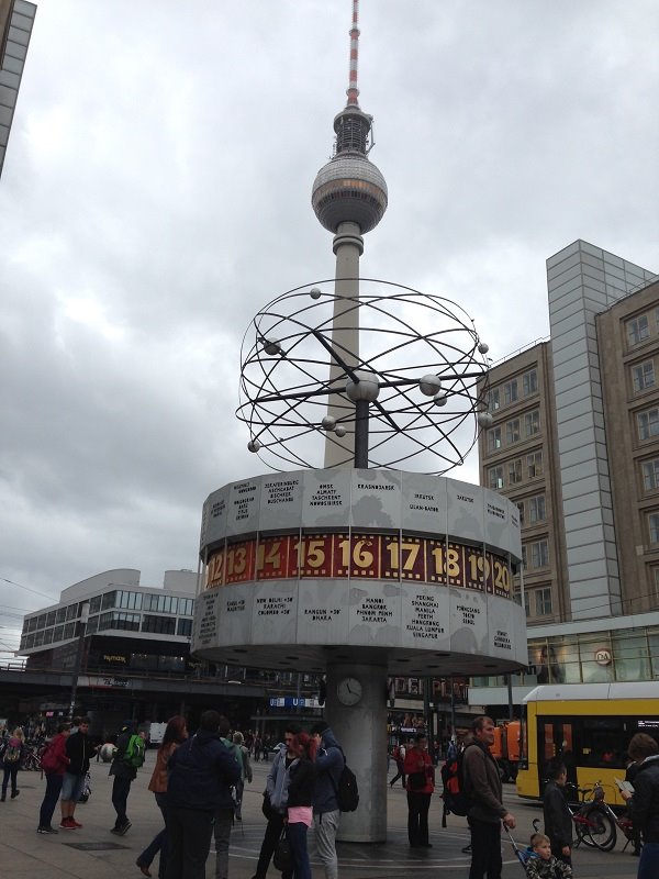 Orologio mondiale e Torre della TV in Alexanderplatz, Berlino, cielo nuvoloso, turisti passano
