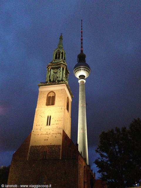 Berlin's Marienkirche lit up beside the Fernsehturm tower at dusk