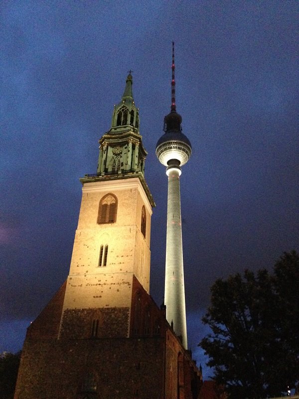 La Marienkirche illuminata accanto alla Fernsehturm di Berlino al crepuscolo