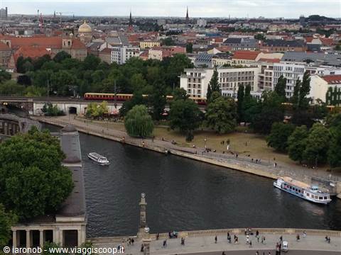 Red city train along the Spree river, boats and people on Berlin's riverside promenade