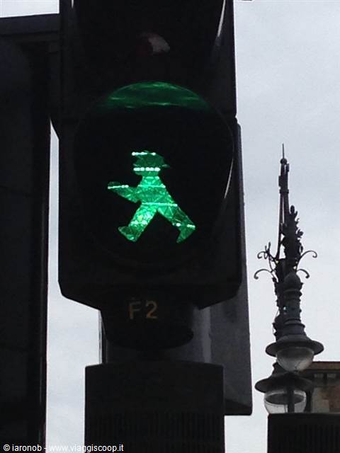 Berlin's green Ampelmännchen lights up the pedestrian signal under a grey sky