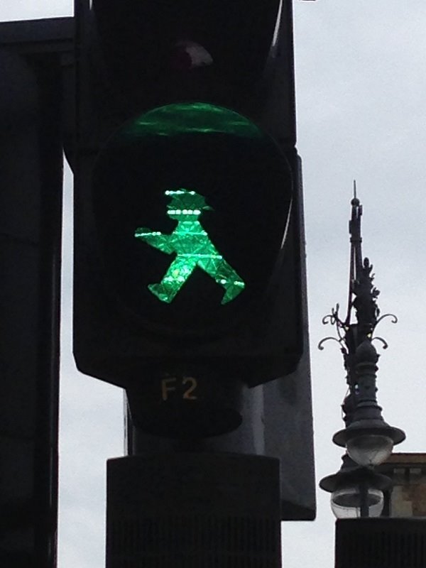 L'Ampelmännchen verde di Berlino accende il segnale pedonale sotto il cielo grigio