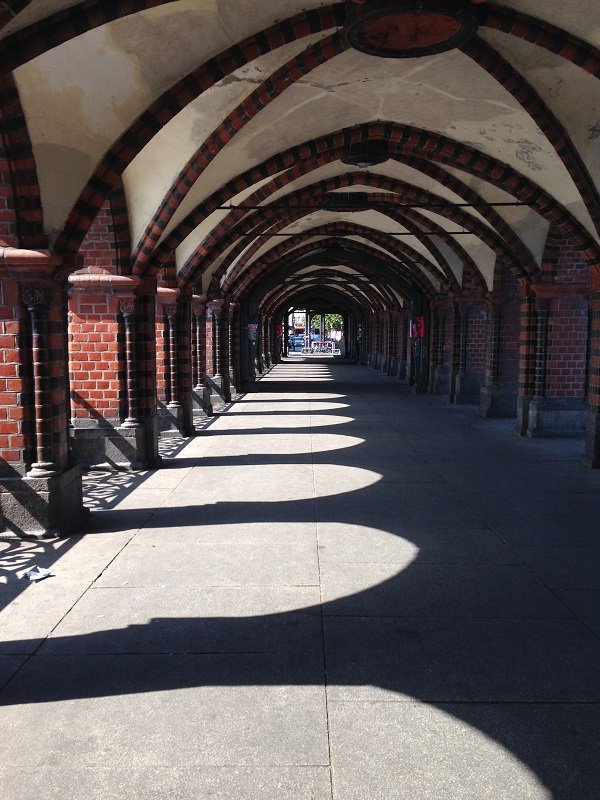 Portico in mattoni rossi con volte a crociera, ombre delle arcate sul pavimento