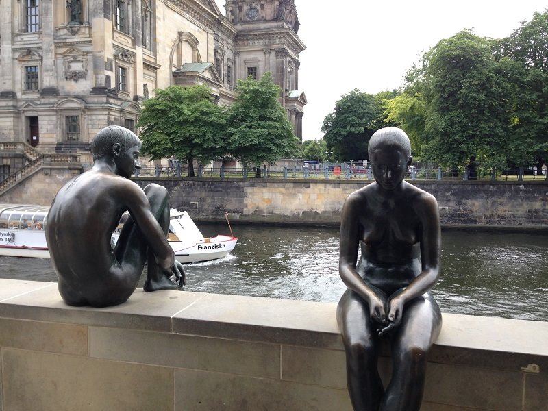 Due statue di bronzo nude sedute lungo il fiume Sprea a Berlino