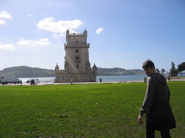 Tourist on the lawn in front of Belém Tower, pale stone, blue Lisbon sky