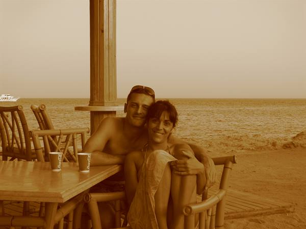 couple embracing at a rattan beach bar, Coca-Cola cups on the table