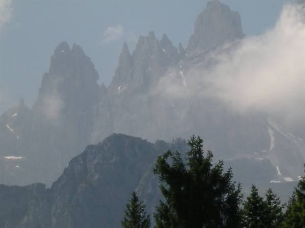 Foggy Dolomite rock spires rising above dark fir trees