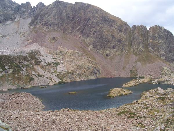 Alpine lake surrounded by scree and granite ridges under overcast sky