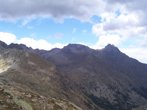 Rocky peaks and scree under white clouds and blue sky