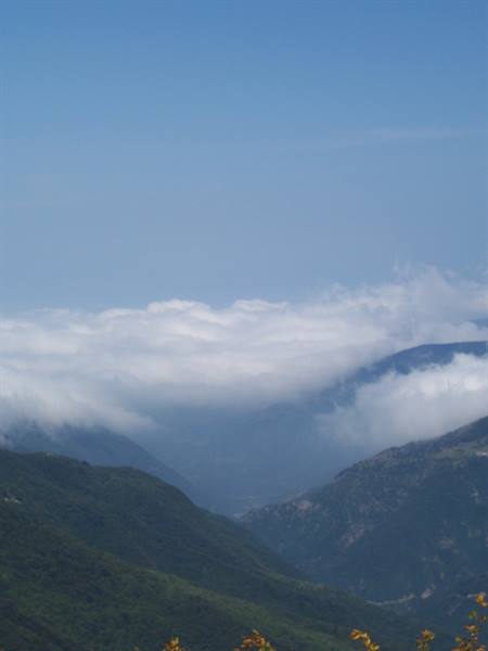 Low clouds drift across valleys between lush green mountains