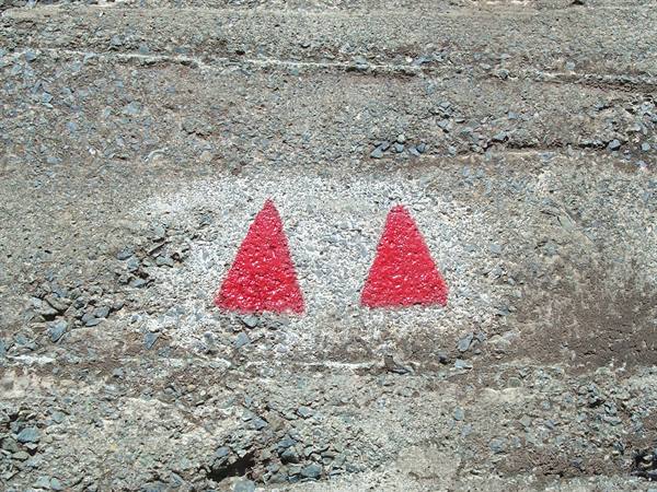 Two red painted triangles mark the trail on grey stone