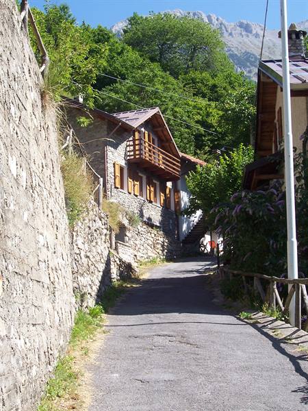 Stone house with wooden balcony along a narrow mountain road