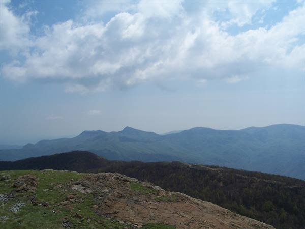 Grassy rocky ridge in the Apuan Alps, blue mountains under scattered clouds