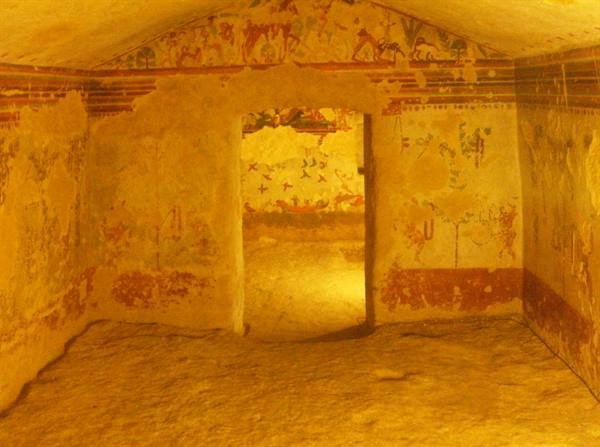 Interior of an Etruscan tomb with frescoed walls and central doorway