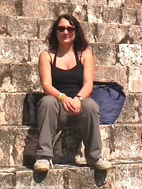 Woman sitting on stone steps of a Mayan pyramid, harsh sunlight