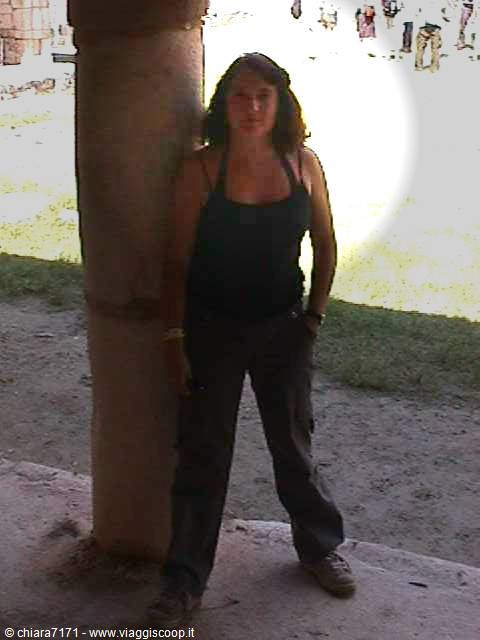 Woman leaning against a stone column under a sunlit colonnade