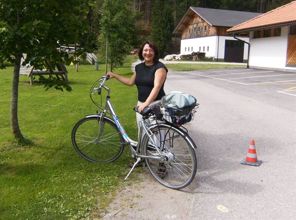 Smiling woman standing next to a gray bicycle with rear basket