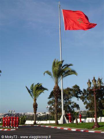Red-uniformed royal guard beneath Morocco's flag outside the Royal Palace in Rabat