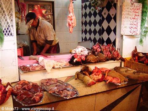Butcher at work in the souk meat stall, hanging meat and marble trays