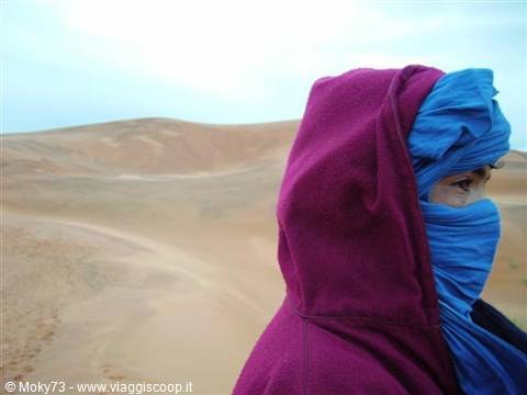 Woman in blue veil and purple shawl among the sand dunes