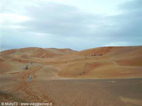 Tourists walking on the sand dunes of Erg Chebbi, Merzouga, under cloudy sky
