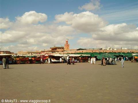 Jemaa el-Fna square in Marrakech: carriages, market stalls and minaret under white clouds