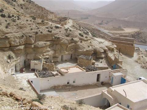 Berber village with cave houses carved into rock below arid hills, Toujane