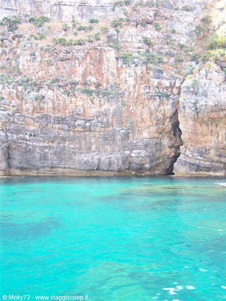 Limestone cliff with sea cave, clear turquoise water, daylight