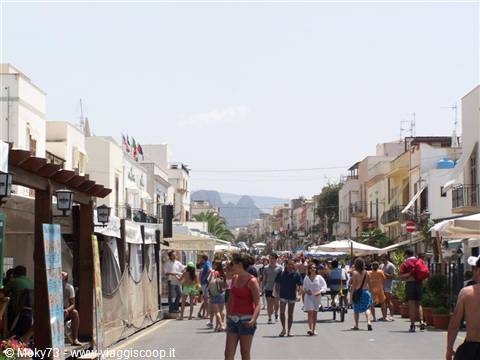 Tourists stroll along a crowded pedestrian street among white buildings, San Vito Lo Capo