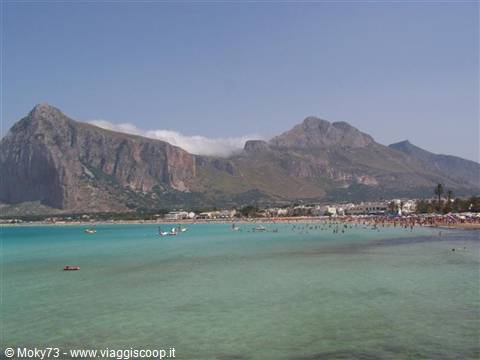 Swimmers in turquoise water at San Vito Lo Capo beneath Monte Monaco