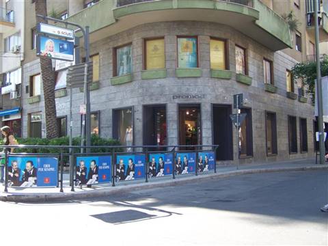 Urban corner with stone building, shop windows and blue advertising banners along the street