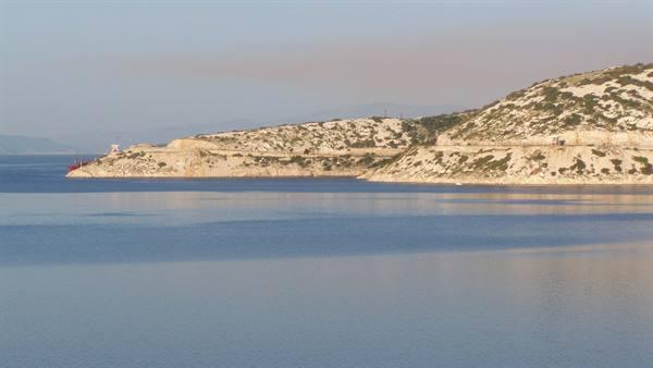 Rocky arid hill above calm blue sea in soft morning light