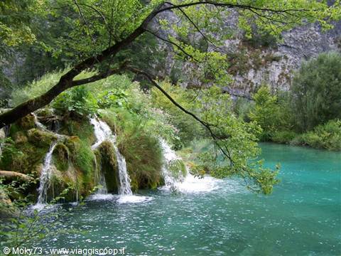 Small waterfalls cascade over green moss into Plitvice's turquoise lake