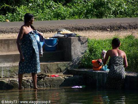 Two women washing at stone steps by the roadside